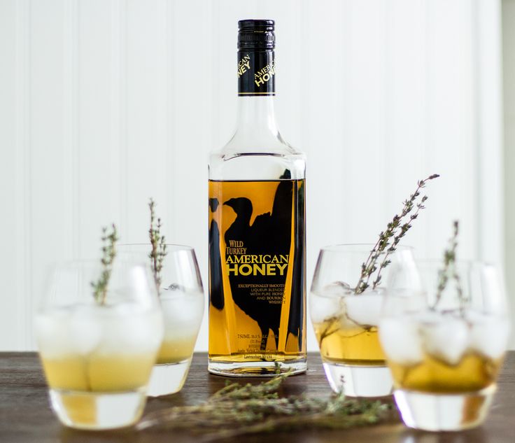 a bottle of american honey sitting on top of a table next to glasses filled with liquid