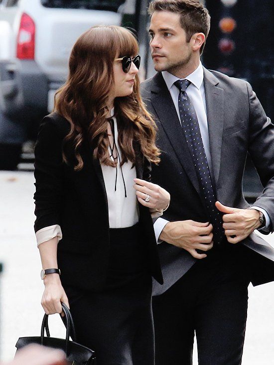 a man in a suit and tie walking next to a woman with a handbag