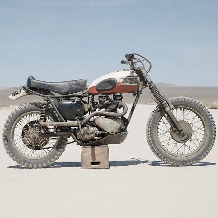 an old dirt bike is parked in the middle of the desert with no one around it