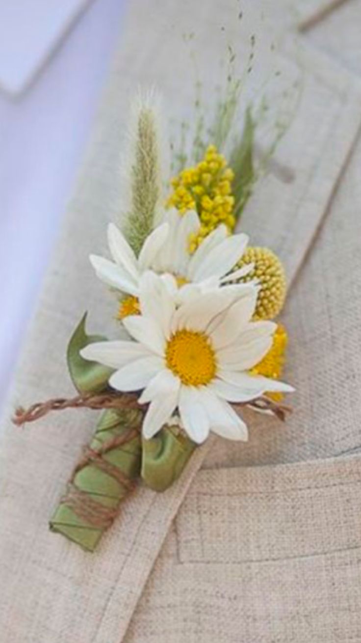 a boutonniere with white and yellow flowers on it's lapel