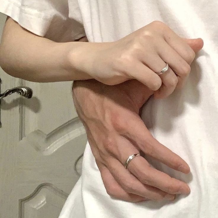 a man and woman are holding hands in front of a mirror with their wedding rings on them