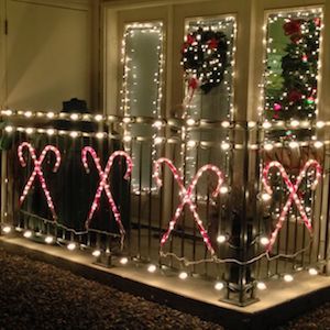 christmas lights on the balcony of a house decorated with candy canes and wreaths