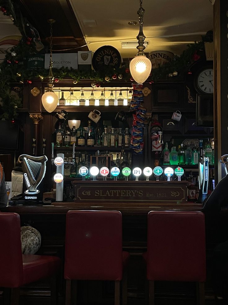 a bar with red chairs and lights hanging from the ceiling