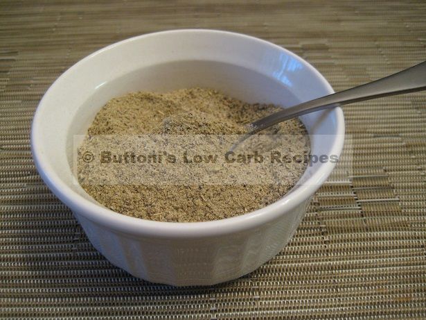 a white bowl filled with sand and a spoon on top of a table next to a bamboo mat