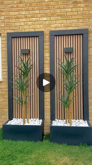 two planters in front of a brick wall with wooden slats on the doors