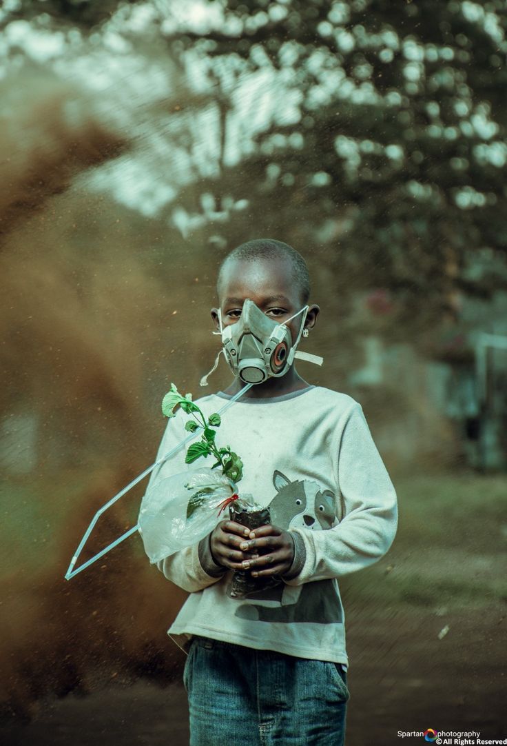 a man wearing a gas mask and holding a plant in his hands while standing outside