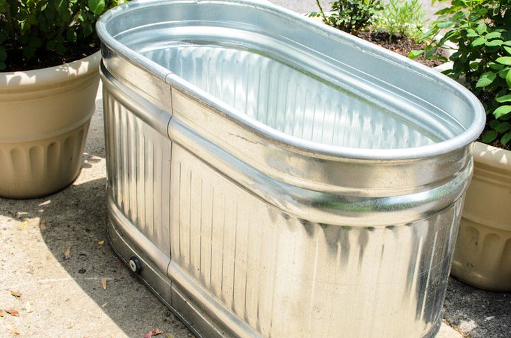 an outdoor bath tub sitting next to some potted plants