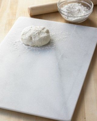 a doughnut on a baking sheet with rolling pin and flour in the bowl next to it