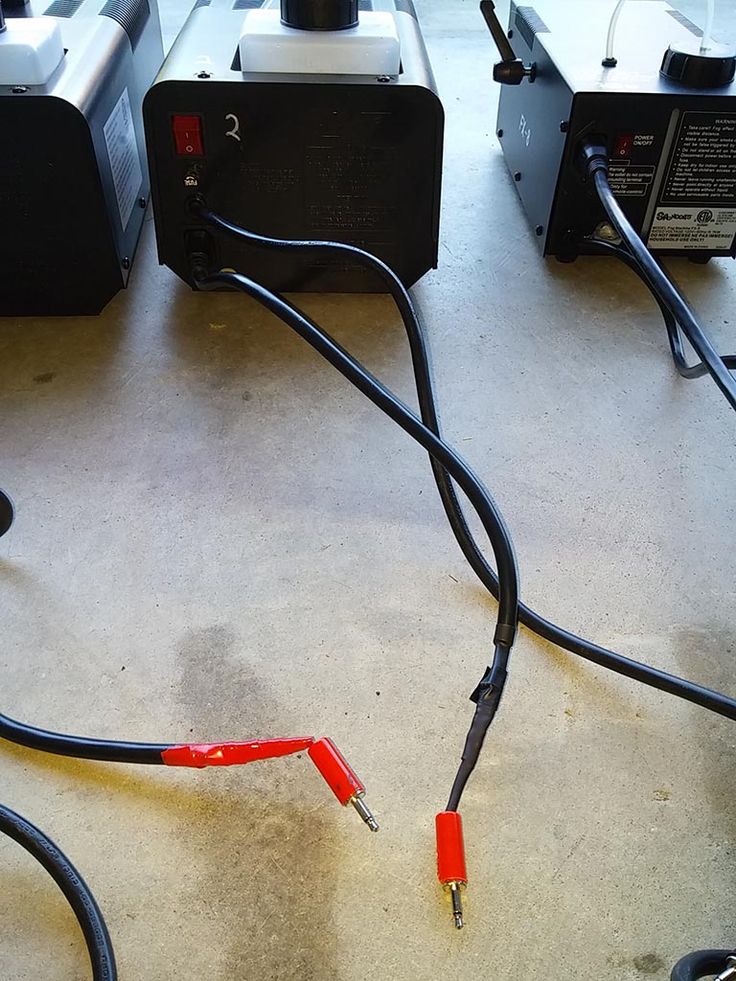 some wires are plugged in and out of the back of an electronic device on the floor