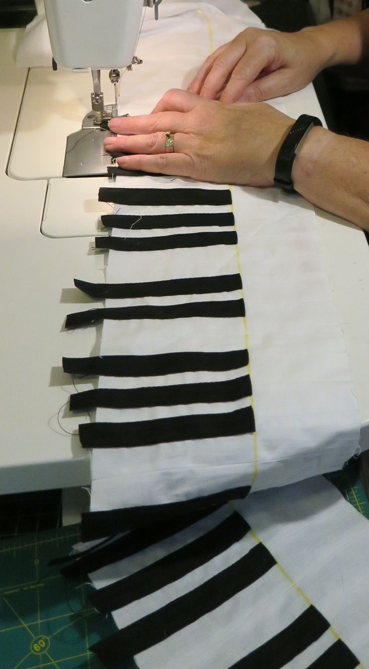 a woman is using a sewing machine to sew black and white striped fabric