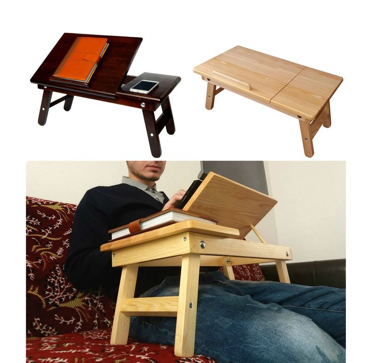 a man sitting on a couch using a laptop computer next to a small wooden table