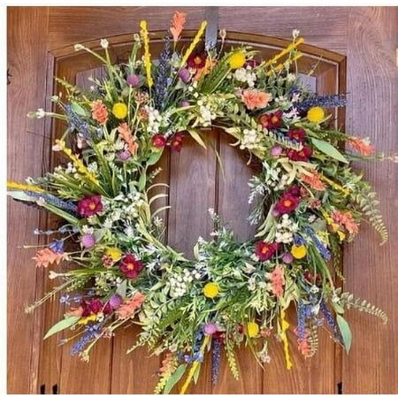 a wreath is hanging on the door with flowers and leaves around it, as well as other decorations