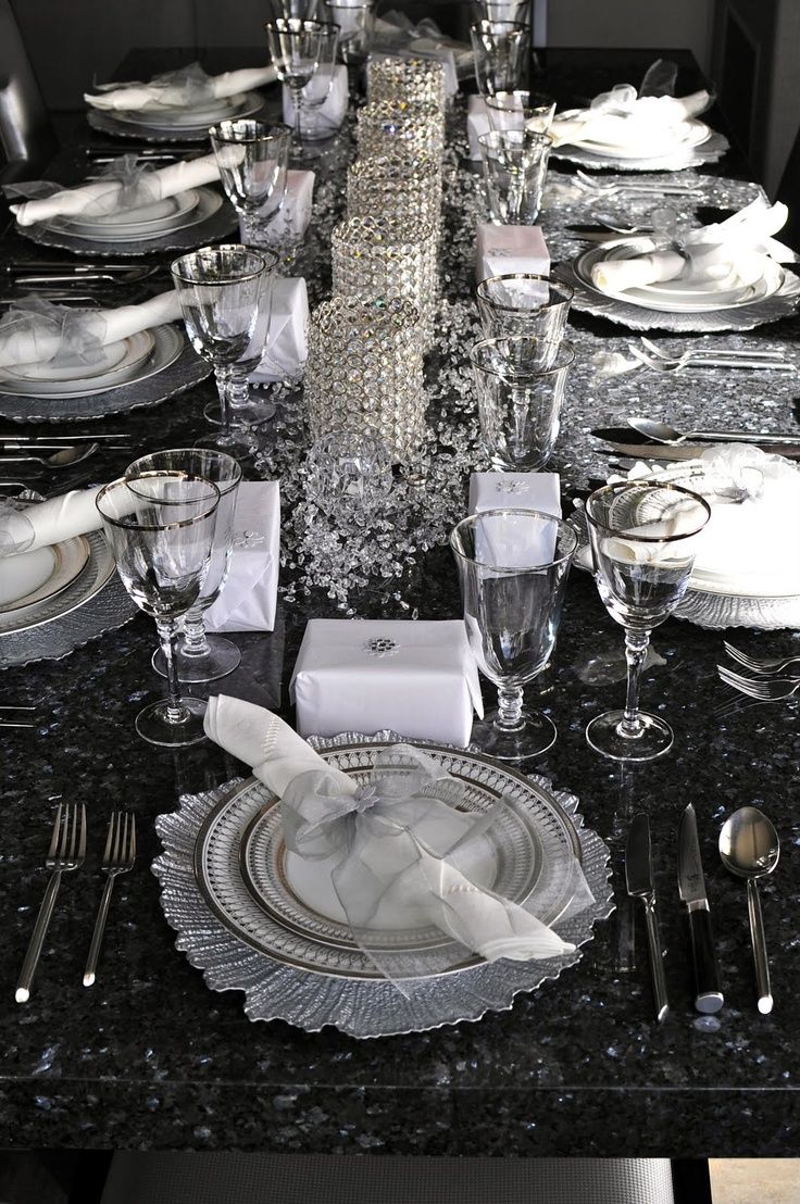 the table is set with silver and white plates, silverware, and napkins