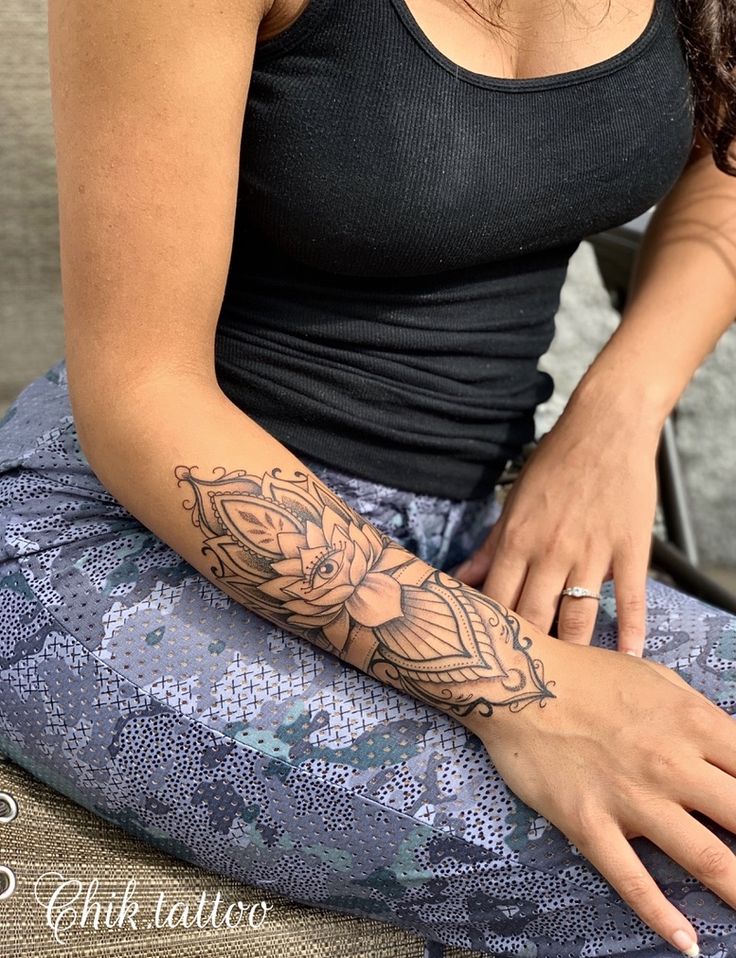 a woman with a tattoo on her arm sitting down and looking at the camera,