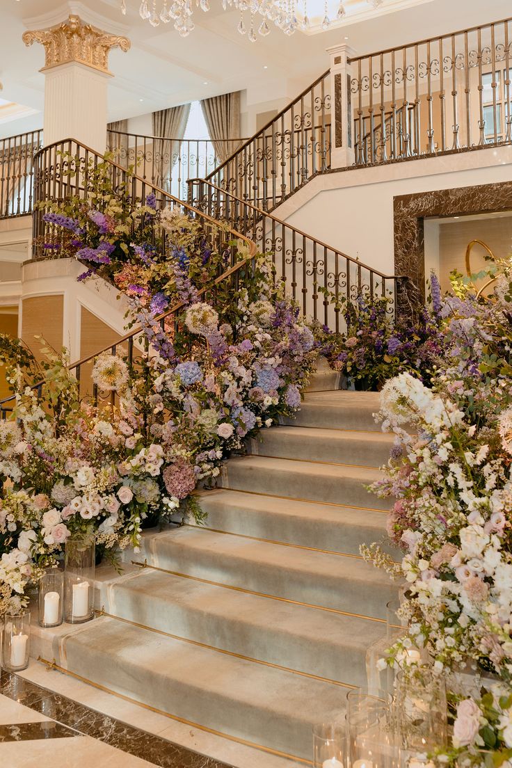 the stairs are lined with flowers and candles in front of chandeliers that hang from the ceiling