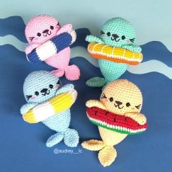 four crocheted stuffed animals sitting on top of a blue surface with water in the background