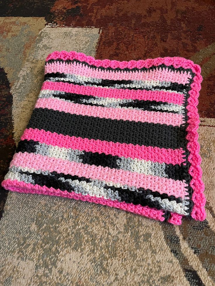 a pink and black crocheted cushion sitting on top of a rug