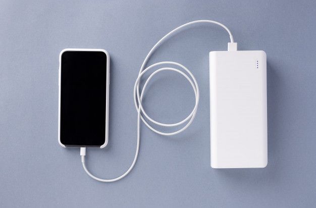 an external charger and power bank on a gray surface with a white cord connected to it