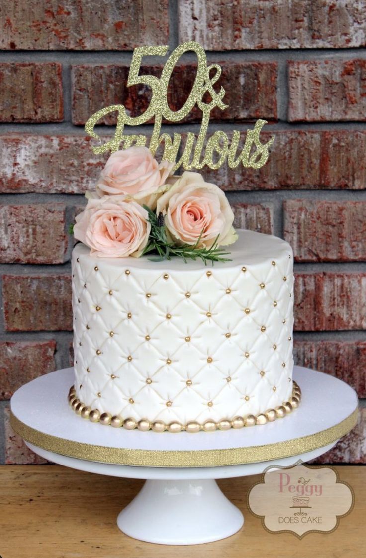 a white cake sitting on top of a wooden table next to a sign that says 50 and fabulous