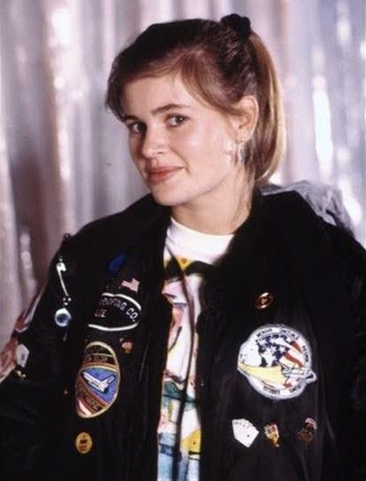 a woman in a black jacket with patches on it