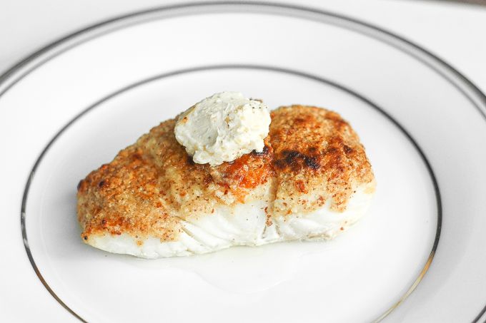 a white plate topped with fish covered in cream