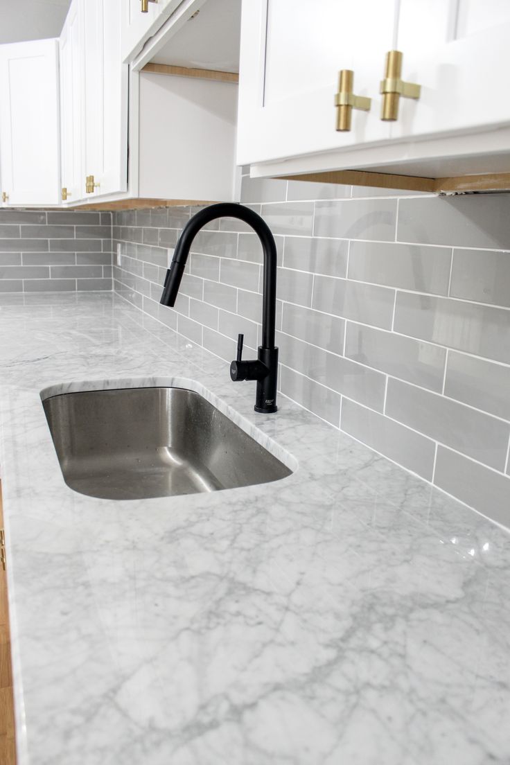 a kitchen with marble counter tops and gold faucet handles on the sink, along with white cabinets