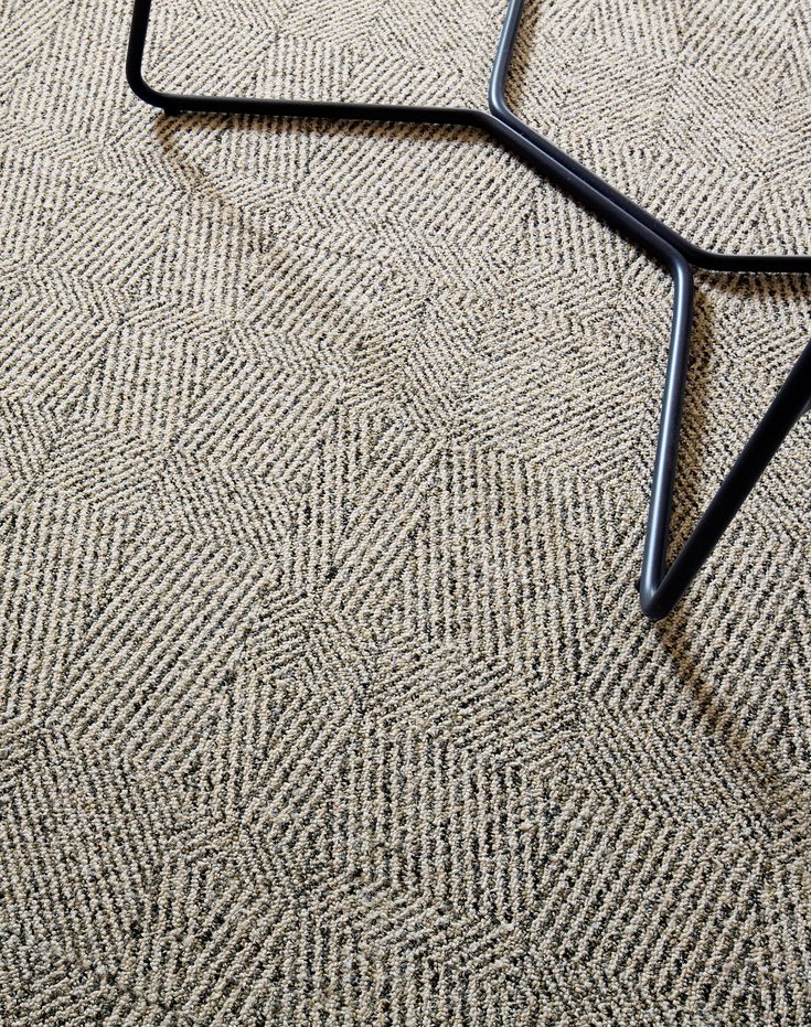 a black metal frame on the floor with a brown carpet and white rug behind it