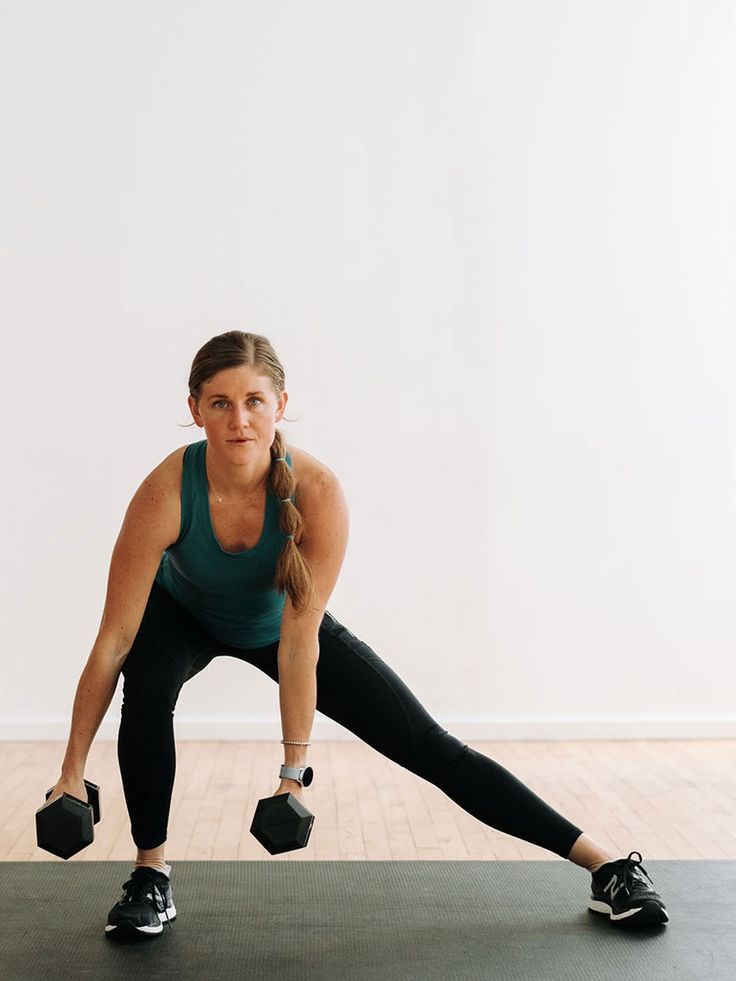 a woman is standing on one leg with two dumbbells in front of her