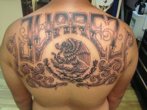 the back of a man's upper half with an eagle tattoo on his shoulder