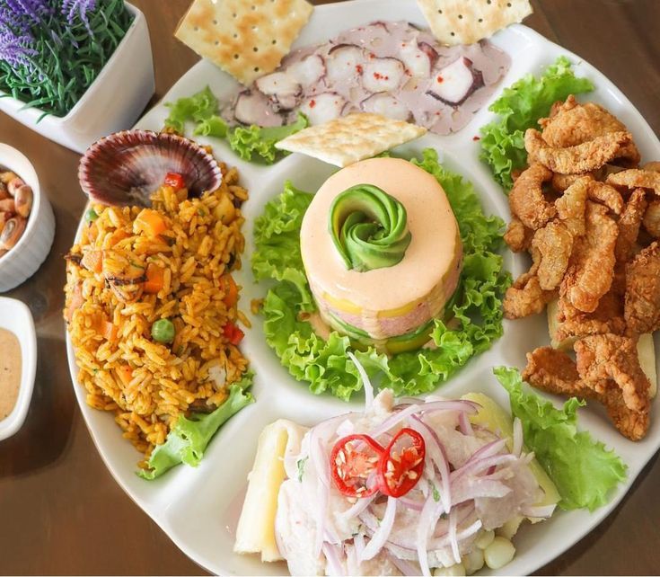 a white plate topped with lots of different types of food next to dipping sauces