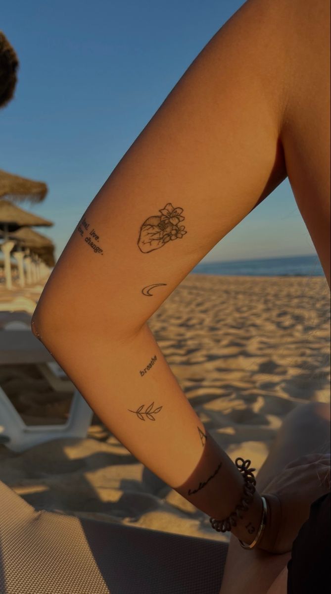 a woman's arm with tattoos on it sitting in front of a beach chair