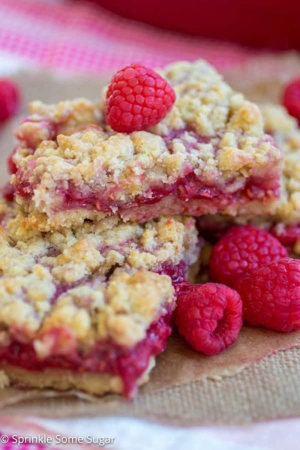 raspberry crumb bars stacked on top of each other with fresh raspberries