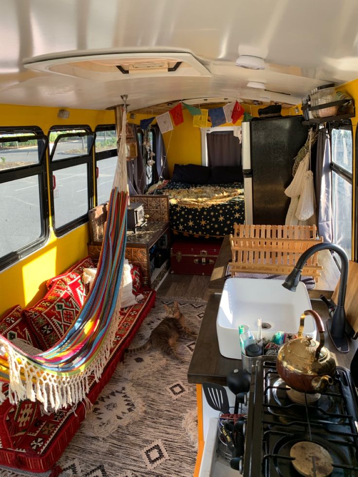 the interior of a bus with hammocks hanging from it's ceiling and windows