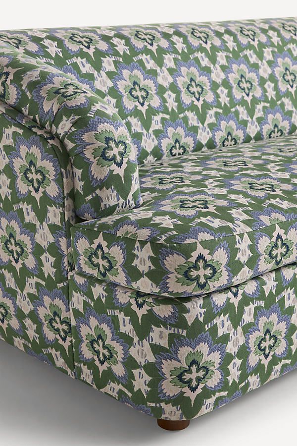 a green and blue patterned couch sitting on top of a white floor