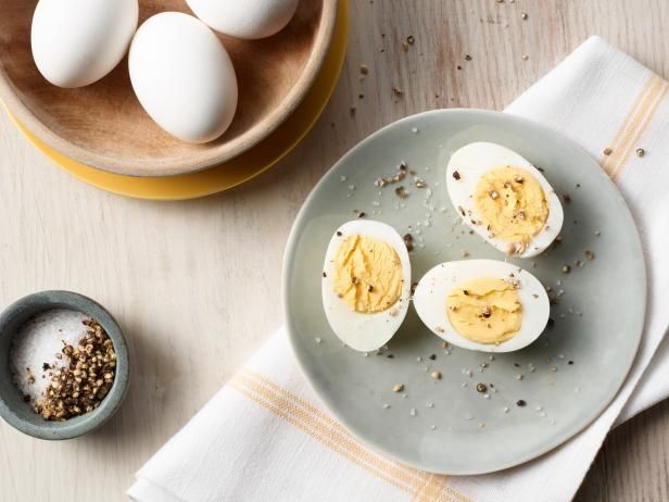 three hard boiled eggs sitting on a plate next to a bowl of salt and pepper