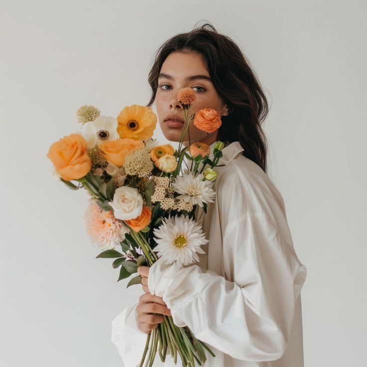 a woman holding a bouquet of flowers in front of her face and looking at the camera