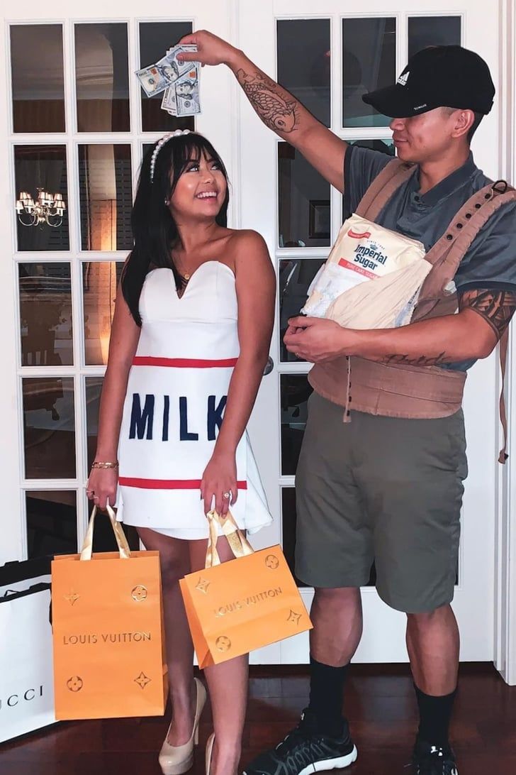 a man and woman are dressed up for halloween with bags on their heads, one is pointing at the other's head