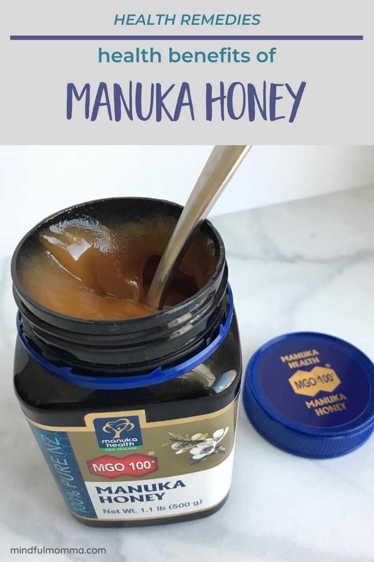 a jar of manuka honey with a spoon in it next to a blue container