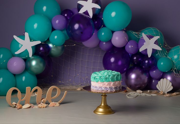 a cake sitting on top of a table next to some balloons and starfish decorations