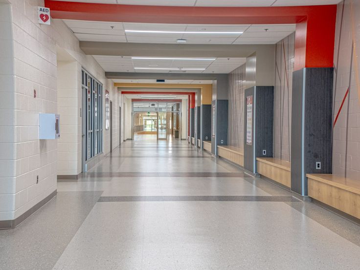 an empty hallway in a school with red accents