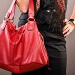 a woman is holding a red purse and talking on the phone