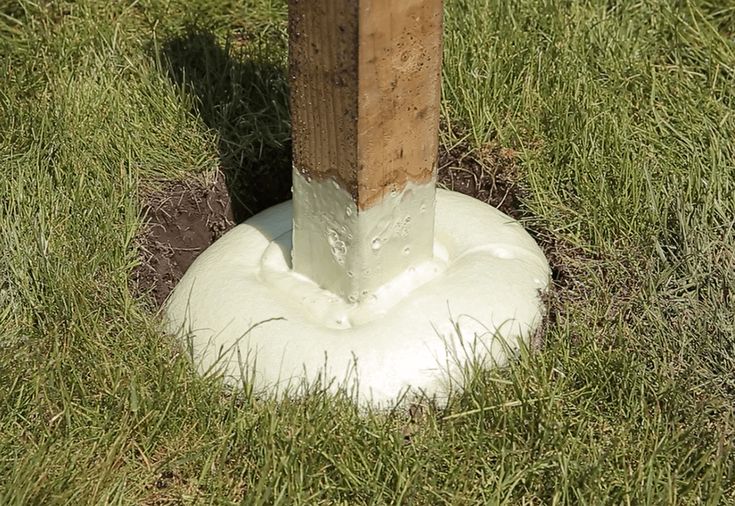 a wooden post sticking out of the ground next to a white object in some grass