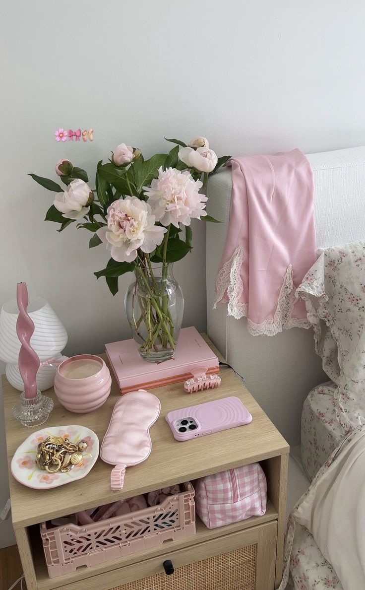 a vase filled with pink flowers sitting on top of a table next to a bed