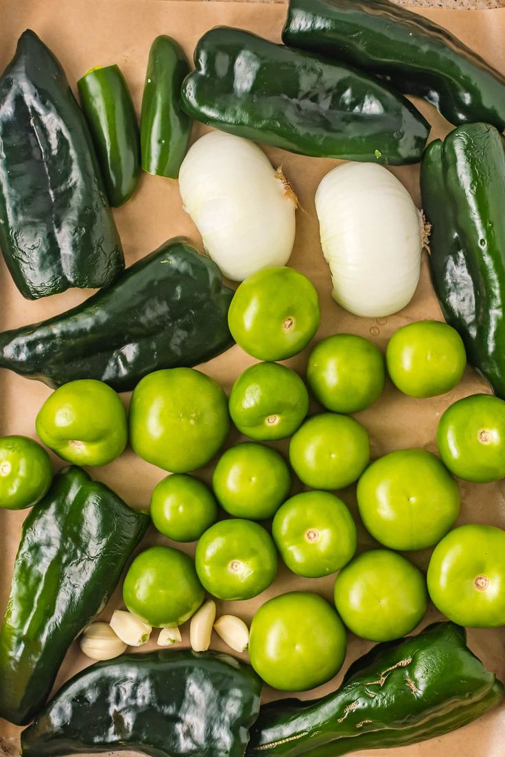 green peppers, garlic and onions on a brown paper bag next to an eggplant