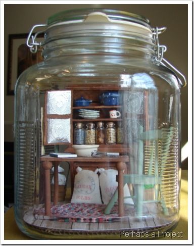 a glass jar filled with lots of stuff on top of a wooden table next to a shelf