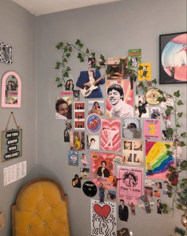 a wall with many pictures on it and a chair in front of the wall has a plant growing out of it