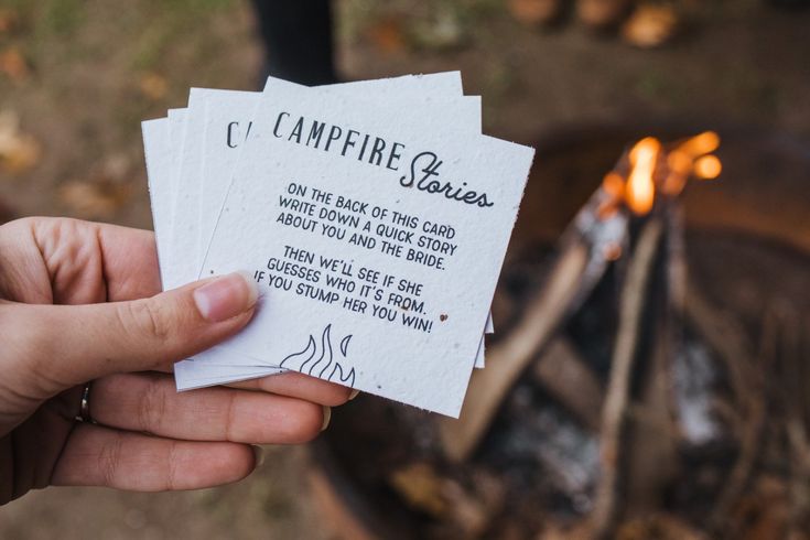 someone is holding up some paper that says campfire stories next to an open fire pit