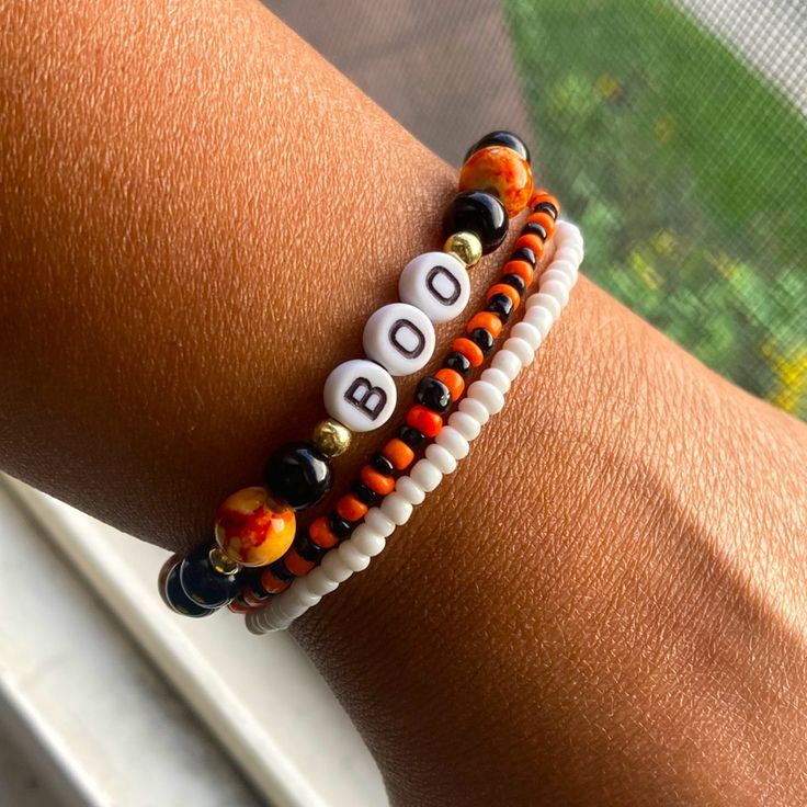 a close up of a person's arm wearing two bracelets with letters on them