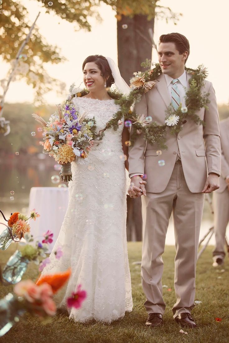 a bride and groom are walking down the aisle with bubbles in their hands as they walk through the grass