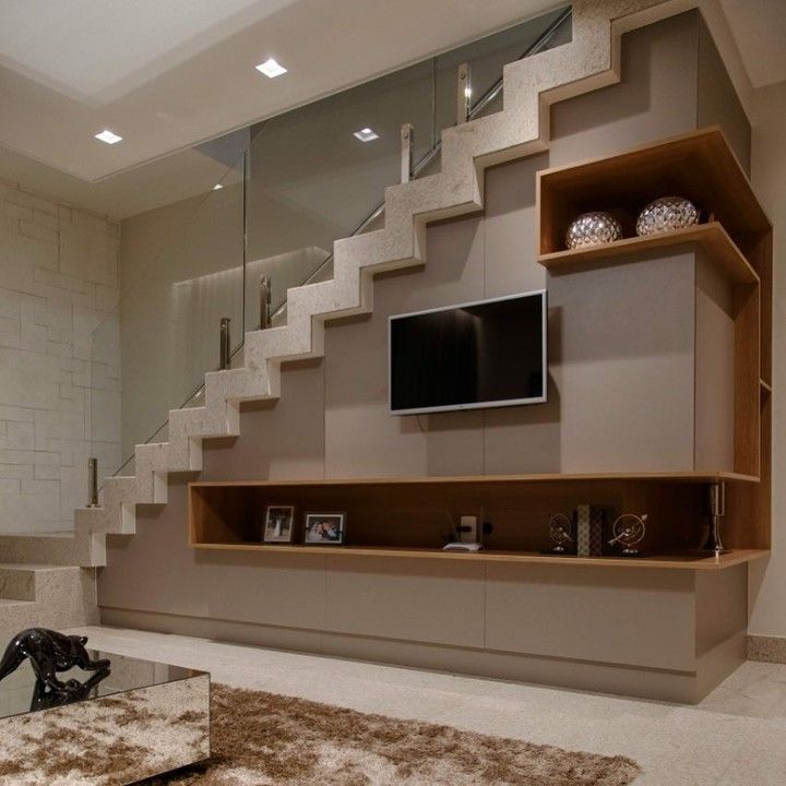 a living room with a tv on the wall next to some shelves and rugs